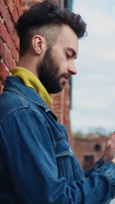 A man is casually using his smartphone outdoors in a modern urban setting full Stock Footage 314209944