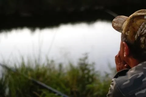 Man catching fish, pulling rod while fishing from lake or pond. Fisherman w.. Stock Photos