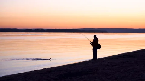 A man caught a fish. A silhouette of a man fishing at sunrise by the river. The Stock Footage 133573917