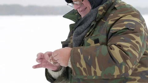 The man caught a small fish on ice fishing. He takes it off the hook and throws Stock Footage 71955364