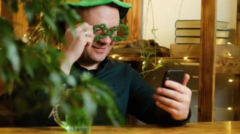 Man celebrating Saint Patricks using smartphone. Stock Photos
