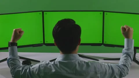 Man Celebrating While Working With Mock Up Multiple Computer Monitor In Green Stock Footage 249633592