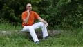 Man with a cell phone sits on a fallen tree in the forest HD Footage