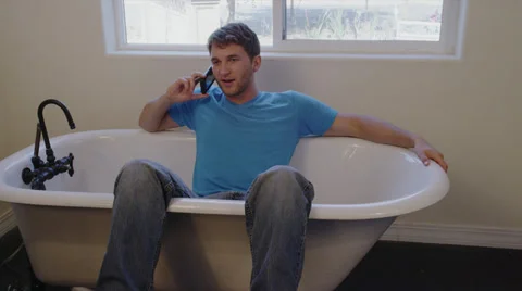 Man on Cell Phone Sitting in Empty Tub Stock Footage 35297987