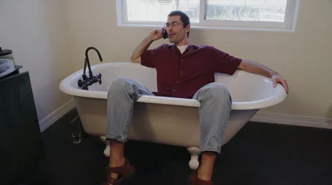 Man on Cell Phone Sitting in Empty Tub Stock Footage 35298140