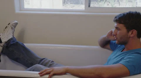 Man on Cell Phone Sitting in Empty Tub with Shoes On Stock Footage 35298365