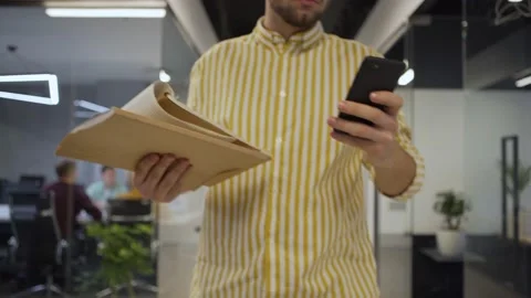 Man with cell phone walking down office corridor 스톡 동영상 132941556