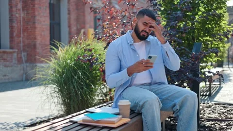 Man with cellphone frowning when feeling sharp headache and massaging forehead Video stock 250075472