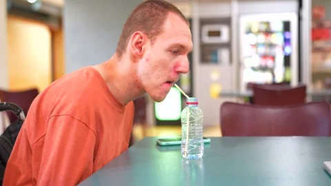 Man with cerebral palsy drinking water helped by straw Stock Footage 278965138