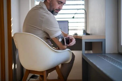 Man with CGM sensor is checking blood glucose level using smartphone app. Stock Photos