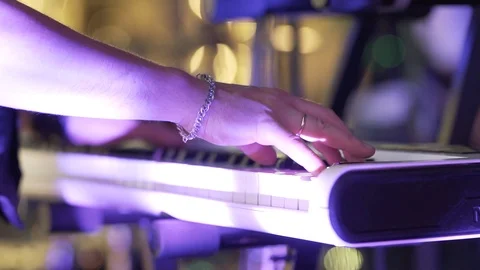 A man with a chain on his arm performs a song by pressing keys on a synthesizer. Stock Footage 126568677