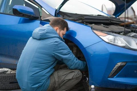 A man changes the brake fluid in a blue car Stock Photos