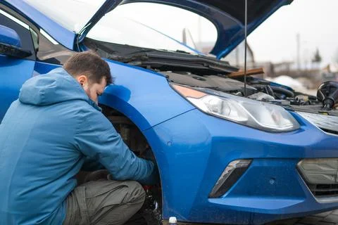 A man changes the brake fluid in a blue car Stock Photos