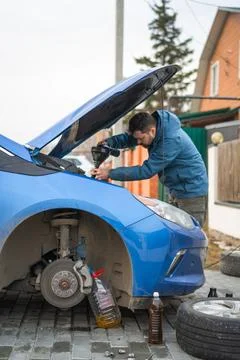 A man changes the brake fluid in a blue car Stock Photos