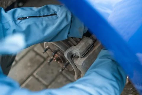 A man changes the brake fluid in a blue car Stock Photos
