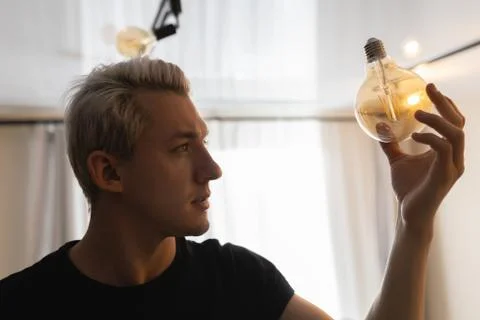 A man changes a burnt out light bulb at home Stock Photos