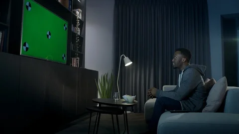 Man changes the channel on his tv while relaxing at home in front of the tv Stock Footage 100191099