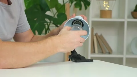 A man changes an electric lamp. Warm yellow light. Replacement an energy-saving Stock Footage 218162534