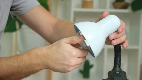 A man changes an electric lamp. Warm yellow light. Replacement an energy-saving Stock Footage 218614450