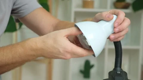 A man changes an electric lamp. Warm yellow light. Replacement an energy-saving Stock Footage 220523059