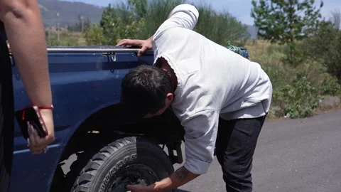 Man changes flat tire on a rural road in Ecuador, October 18, 2024 動画素材 287256848