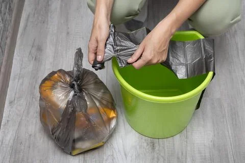 A man changes a garbage bag in a bucket. Stock Photos