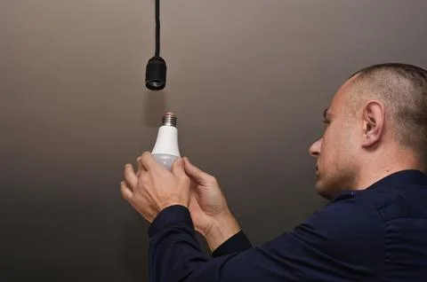 A man changes a light bulb at home Stock Photos