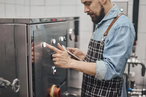 Man changes technological settings at the brewery. Stock Photos
