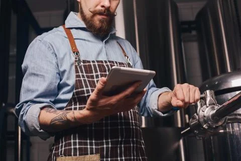 Man changes technological settings at the brewery. Stock Photos