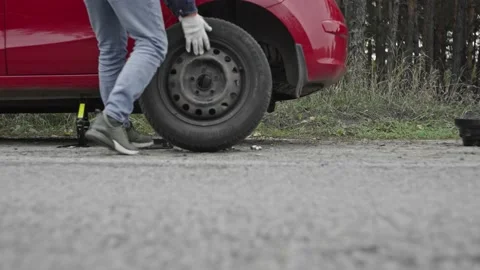 A man changes a tire in a car on the road. Breakdown of the car during the trip Stock Footage 223379197