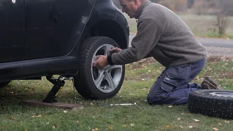 Man changes tires, tightens lugnuts by hand Stock Footage 97402812