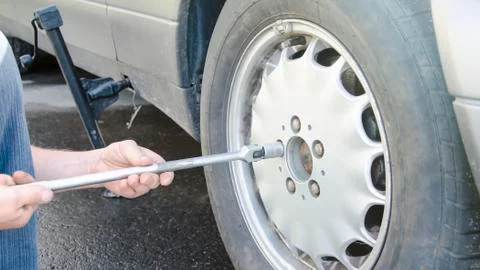 Man changes the wheel on the road, putting the car on the jack Stock Photos