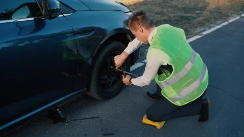 Man changes wheels on a car. unscrews the wheel nuts with a wrench. car servi Stock Footage 138947921
