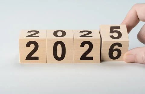 Man changes year from 2025 to 2026 with wooden blocks. Symbolizes new year ev Stock Photos