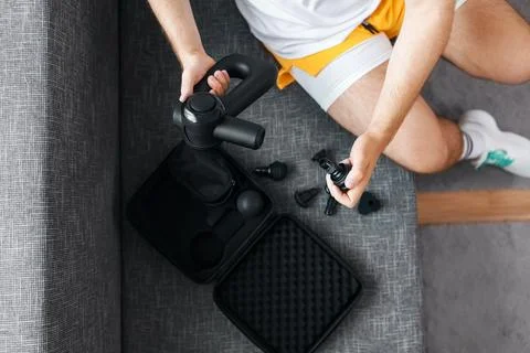 Man changing attachments on a percussion massage gun for post-workout recov.. Stock Photos