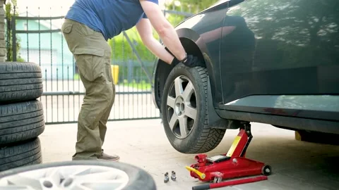 Man changing car wheels at his backyard. 스톡 동영상 198212858