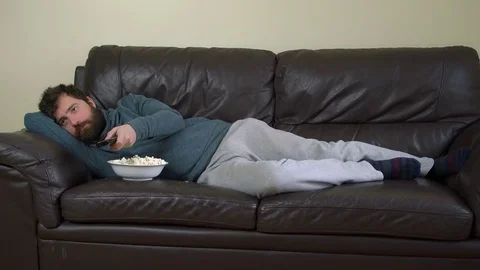 Man Changing Channels with Remote Control, Watching Television on Sofa Stock Footage 76522350