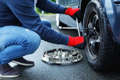 Man changing flat tire on his own car Stock Photos