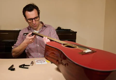 Man Changing Guitar Strings at Home - Guitar Maintenance and Repair Tutorial 스톡 사진