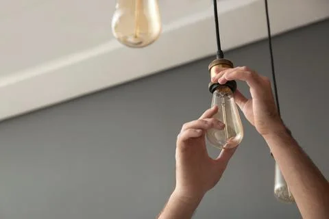 Man changing lamp light bulb indoors, closeup. Space for text Stock Photos
