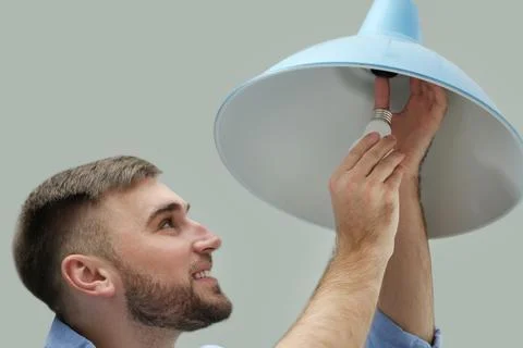 Man changing light bulb in lamp indoors Stock Photos