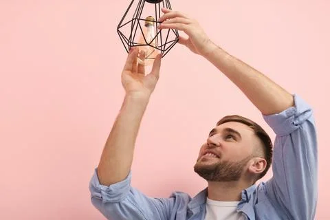 Man changing light bulb in lamp on color background Stock Photos