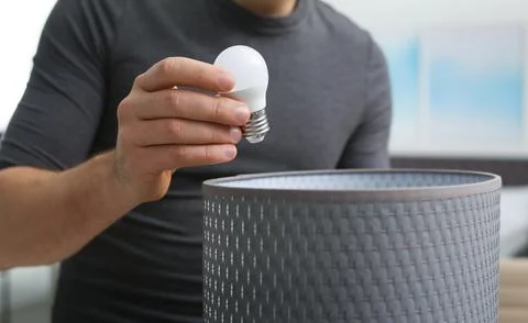 Man changing light bulb in lamp indoors, closeup Stock Photos
