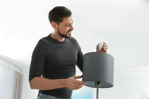 Man changing light bulb in lamp indoors Stock Photos