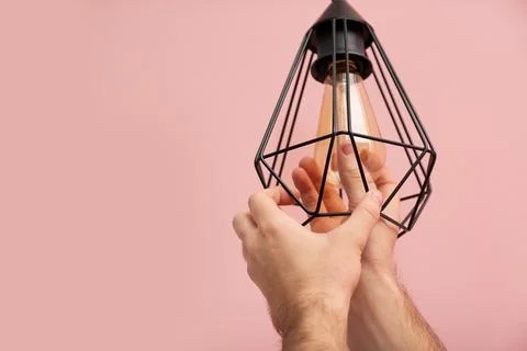 Man changing light bulb in lamp on color background. Space for text Stock Photos
