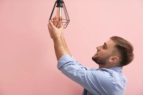 Man changing light bulb in lamp on color background Stock Photos