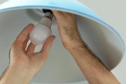 Man changing light bulb in lamp, closeup Stock Photos