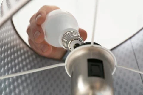 Man changing light bulb in lamp, closeup. Low angle view Stock Photos
