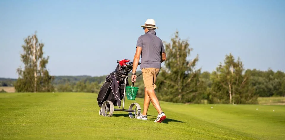 A man changing position on the golf course. Golf player walking with a golf c Stock Photos