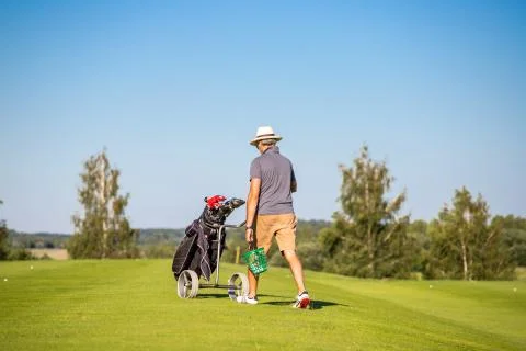 A man changing position on the golf course. Golf player walking with a golf c Stock Photos